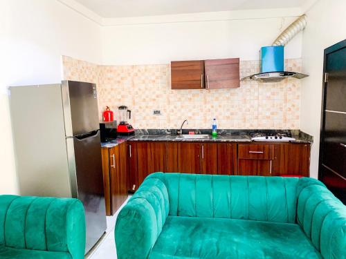 ein Wohnzimmer mit einer grünen Couch in einer Küche in der Unterkunft Yardcourt 3Bedroom in Lagos