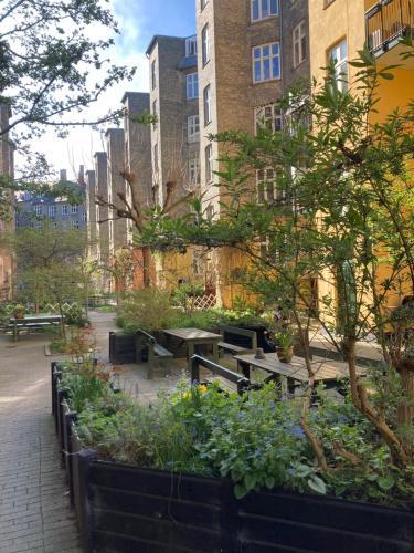 a garden with tables and plants in front of buildings at Globetrotter Hotel in Copenhagen