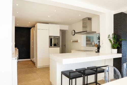 a kitchen with a white counter and stools at Villa prestige (voiture plage) in Carqueiranne
