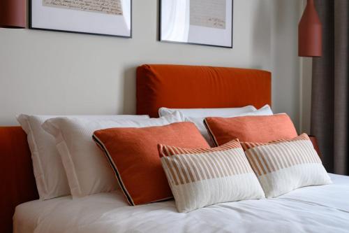 a bed with orange and white pillows on it at GL HOME in Como