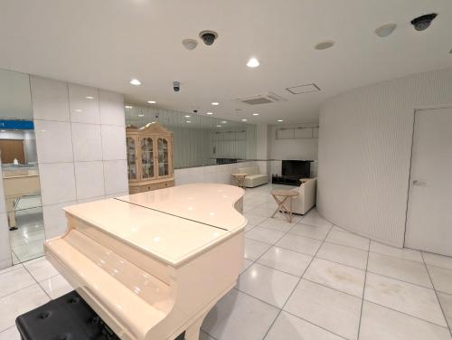 a large kitchen with white tile floors and white walls at 瀬戸内リゾートホテル in Matsuyama