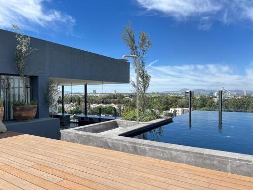 a house with a swimming pool and a wooden deck at Nuevo Departamento con Terraza, Alberca y Gimnasio in Guadalajara