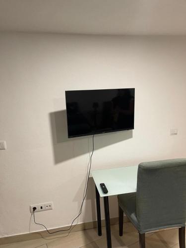 a tv on a wall with a table and a chair at Casa da Martha in Celorico da Beira