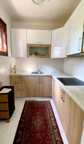 una cucina con mobili bianchi e un tappeto rosso sul pavimento di Dhabi Sweet Home a Doglodi