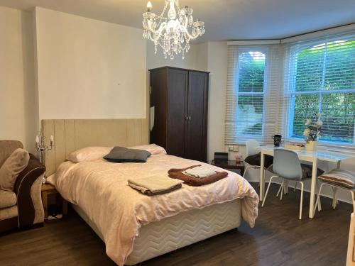 um quarto com uma cama, uma mesa e um lustre em Spacious front bedroom - near The Level - 2 dogs live at the property em Brighton & Hove