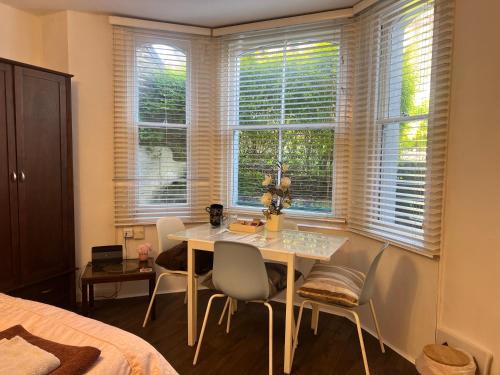 um quarto com uma mesa, cadeiras e janelas em Spacious front bedroom - near The Level - 2 dogs live at the property em Brighton & Hove