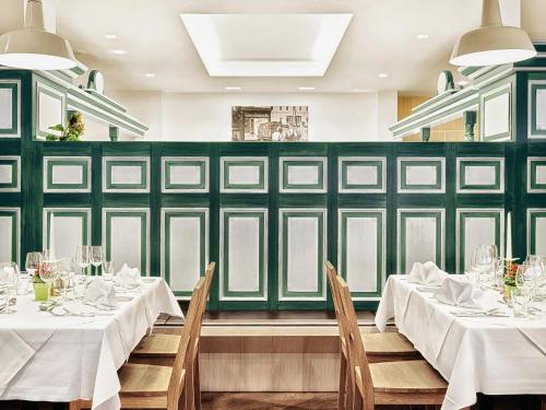 a dining room with white tables and green walls at Alphotel Innsbruck in Innsbruck