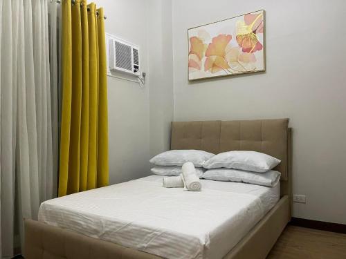a bedroom with a bed with a yellow curtain at Verdon Parc Davao City with Balcony by darpm in Davao City