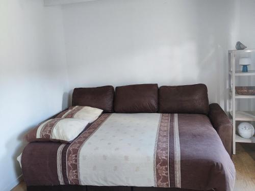 布格奈的住宿－Bienvenu，一张位于带棕色沙发的房间的床铺