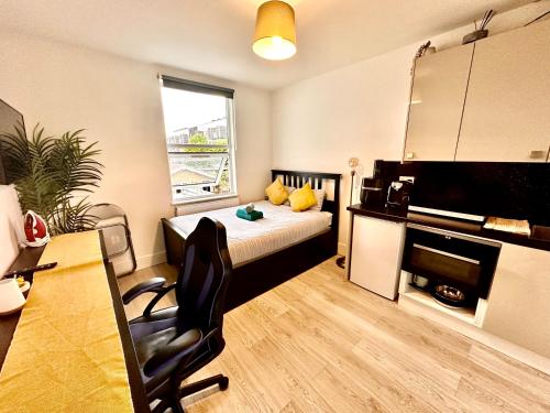 a bedroom with a bed and a desk with a chair at Lovely self contained studio now available in London