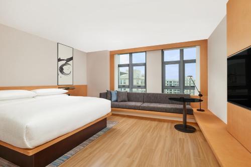 a bedroom with a bed and a couch and windows at Fairfield by Marriott Guangzhou Konggang in Guangzhou
