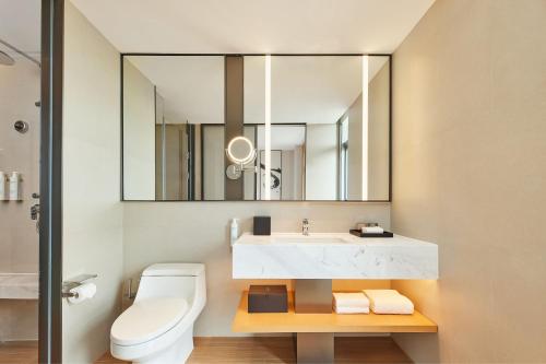 a bathroom with a sink and a toilet and a mirror at Fairfield by Marriott Guangzhou Konggang in Guangzhou