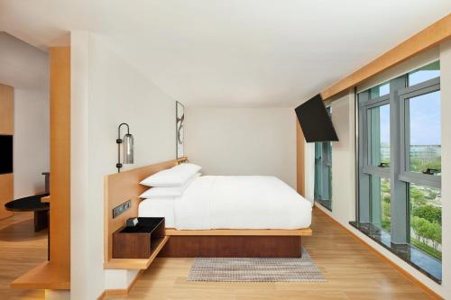 a bedroom with a white bed and a large window at Fairfield by Marriott Guangzhou Konggang in Guangzhou