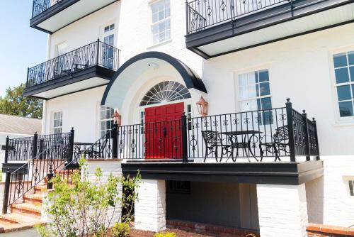 a white house with a red door and a balcony at The Harvey in New Bern