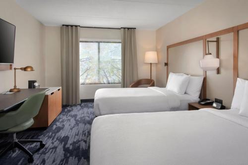 a hotel room with two beds and a desk at Fairfield Inn Rochester Airport in Rochester