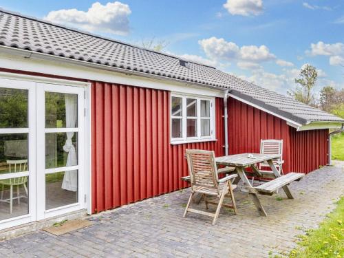 un edificio rojo con mesa de picnic y sillas en 8 person holiday home in Vestervig en Vestervig