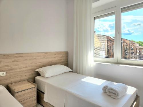 um quarto branco com uma cama e uma janela em Rustic City Center Vibes em Tirana
