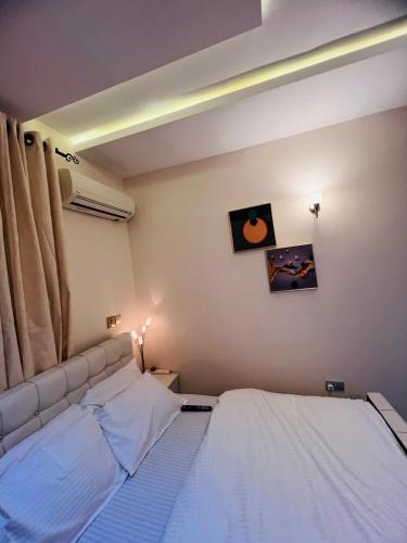 een slaapkamer met een bed met witte lakens bij Apartments by Dee in Port Harcourt