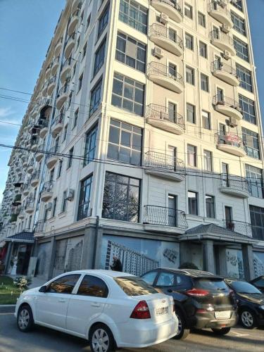 een hoog gebouw met auto's geparkeerd voor het bij Comfort House in Tasjkent