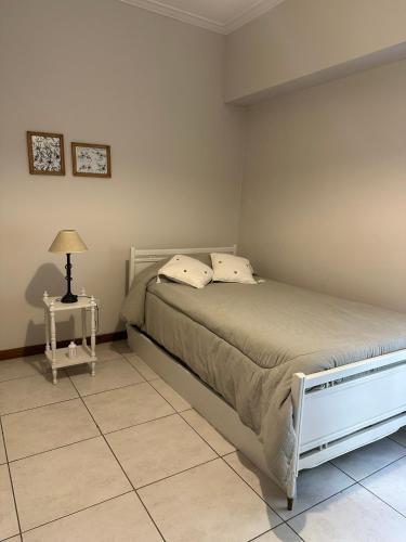 een slaapkamer met een bed en een lamp op een tegelvloer bij Casa Aurora in Olavarría