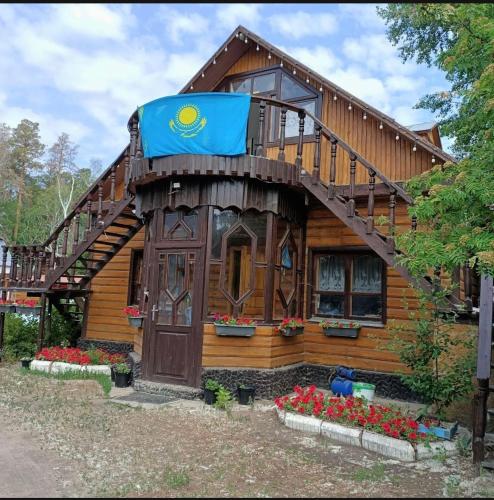 una casa con una bandera en la parte delantera en Гостевой дом ОЛЖАС en Borovoye