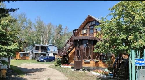 a log house with a balcony on the side of it at Гостевой дом ОЛЖАС in Borovoye