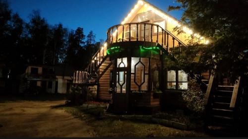 ein Haus mit einer Wendeltreppe davor in der Nacht in der Unterkunft Гостевой дом ОЛЖАС in Borovoye