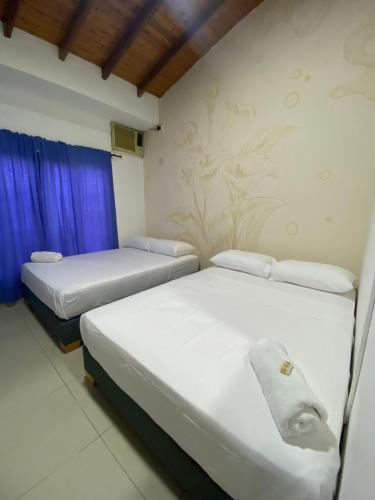 two beds in a room with blue curtains at HOTEL LAS PALMAS in La Virginia