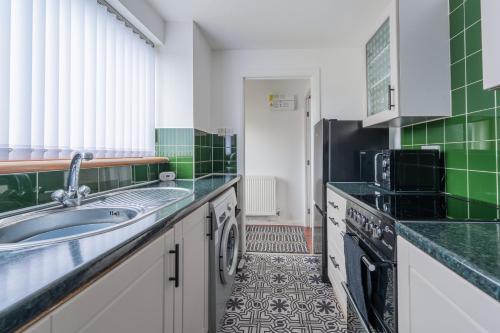 a kitchen with a sink and a dishwasher at A Cosy Home from Home in Oldham