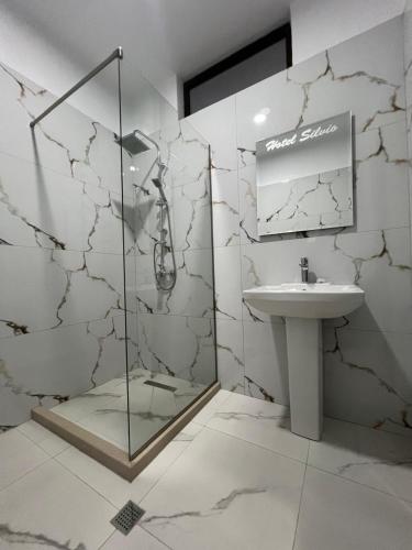 a bathroom with a glass shower and a sink at Hotel Silvio in Fier
