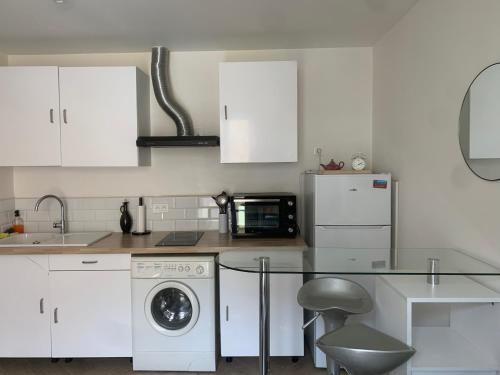 une cuisine avec des armoires blanches et une table en verre dans l'établissement Charmant Appartement à 5 minutes de la plage, à Nice