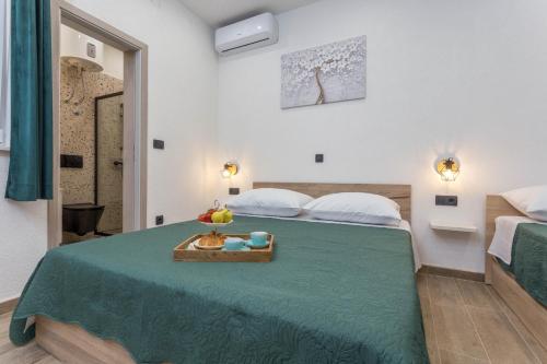 een slaapkamer met een groen bed met daarop een dienblad met fruit bij Apartment Zastupac 8761c in Hvar