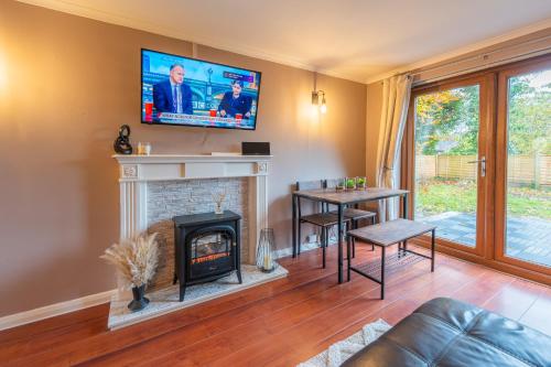 a living room with a fireplace and a flat screen tv at A Cosy Home from Home in Oldham
