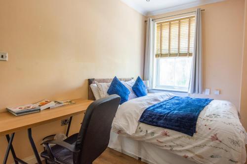 a bedroom with a desk and a bed with blue pillows at Evergreen Apartments, Flat 3, London in London