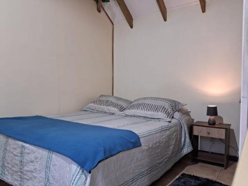 1 dormitorio con 1 cama con sábanas azules y mesita de noche en SEA LODGE ALGARROBO en Algarrobo