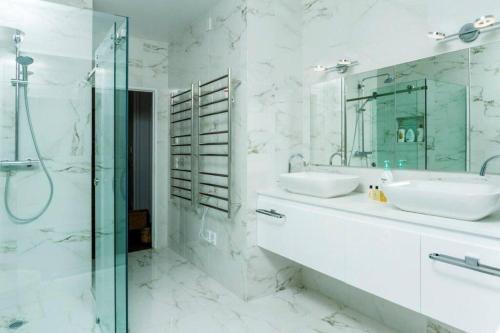a bathroom with two sinks and a glass shower at Beachside Bliss Castor Bay - Holiday by the Beach in Auckland