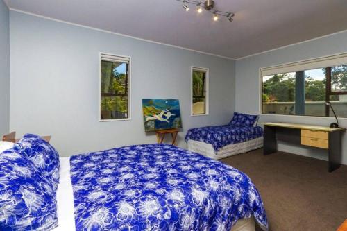a bedroom with a bed and a desk and windows at Beachside Bliss Castor Bay - Holiday by the Beach in Auckland