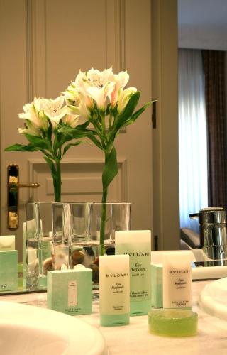 a vase with a flower on a table with labels at Hotel Rector in Salamanca