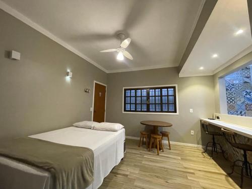 a bedroom with a bed and a table and a window at Chilli Brasil Suite in Ubatuba
