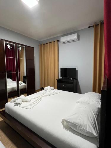 una camera da letto con un grande letto bianco e uno specchio di Hotel Silvio a Fier