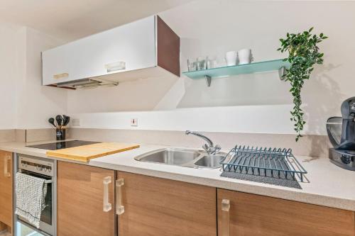 a kitchen with wooden cabinets and a sink at Central Birmingham 2 Bed with Balcony and City Views in Birmingham