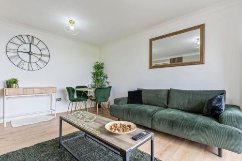 a living room with a green couch and a table at Central Birmingham 2 Bed with Balcony and City Views in Birmingham