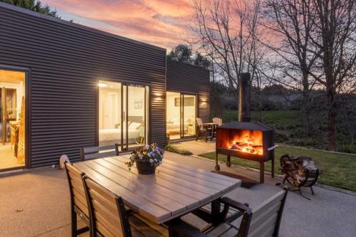 a backyard with a wooden table and a fireplace at 5 o'clock Somewhere in Masterton