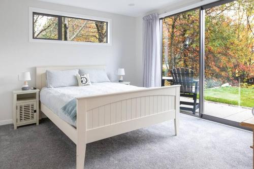 a white bedroom with a bed and a large window at 5 o'clock Somewhere in Masterton