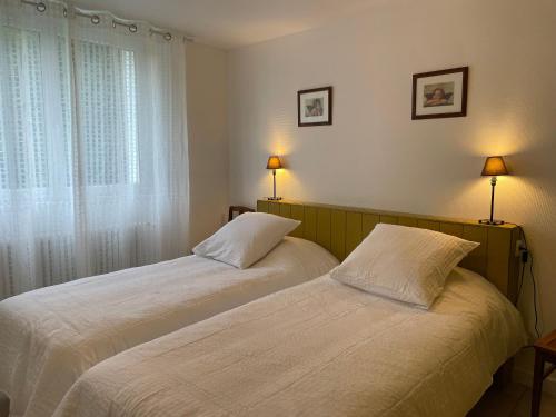 two beds in a bedroom with a window and two lamps at Gîte chaleureux avec jardin arboré, terrasse, salle de jeux et parking privé à Pré-Saint-Évroult. - FR-1-581-3 in Pré-Saint-Évroult