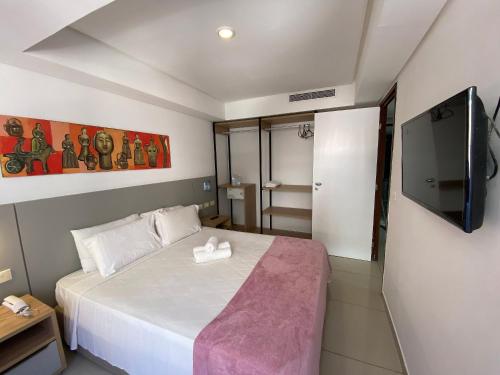 1 dormitorio con 1 cama y TV de pantalla plana en Bela Hospedagem - Marinas Flat - Excelente localização na orla de Cabo Branco en João Pessoa