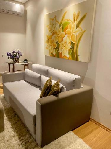 eine Couch in einem Wohnzimmer mit einem Gemälde an der Wand in der Unterkunft Apartamento Lago Negro in Gramado