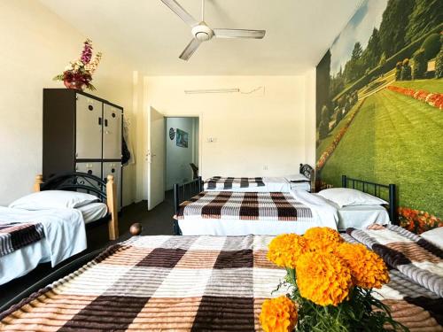 een kamer met drie bedden en een schilderij aan de muur bij Pizza Street Hostel in Aqaba
