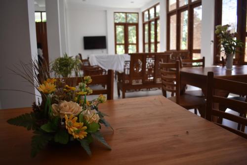 a vase of flowers sitting on a wooden table at SaDev Lake Villa Bandaragama in Bandaragama