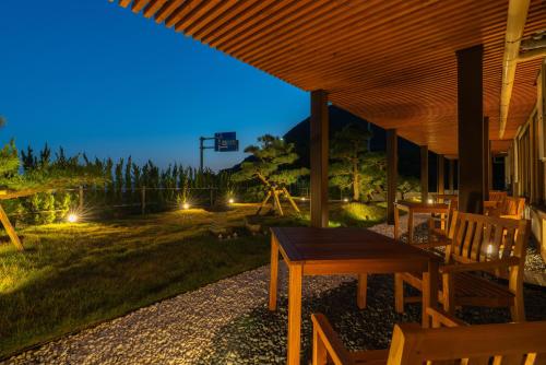 a patio with a wooden table and chairs at night at Isoaruki no Yuyado Ushiogumo -6 years or older- in Kawazu